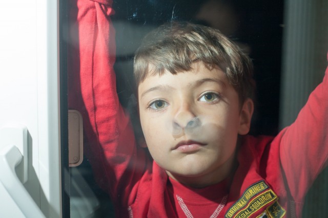 little boy looking through glass window